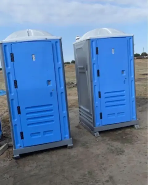 Two porta potties on a dirt construction lot